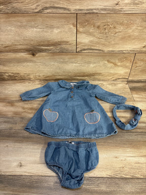 Top-down view of baby blue 3-piece denim set: button-front long-sleeve dress with apple embroidery, bloomers, headband on wood