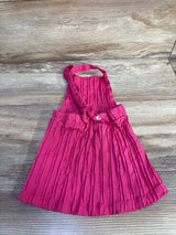 Flat-lay front of pink toddler skirtall with crinkled texture, elastic waist and adjustable straps with heart button on wood