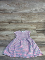 Flat lay of girls' pink patterned dress size 4T showcasing flutter sleeves and gathered skirt with wood floor background