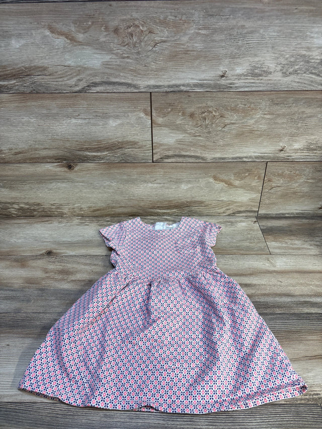 Flat lay of girls' pink patterned dress size 4T showcasing flutter sleeves and gathered skirt with wood floor background