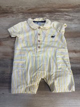 Yellow striped baby romper with front buttons and pockets on wood background