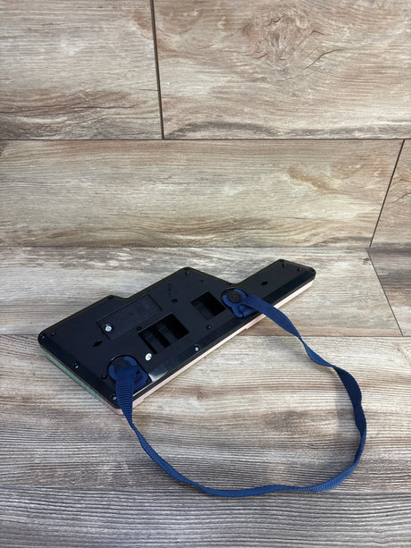 Rear view of VTech Bluey's Keytar showing battery compartment and attached blue strap on wood floor background
