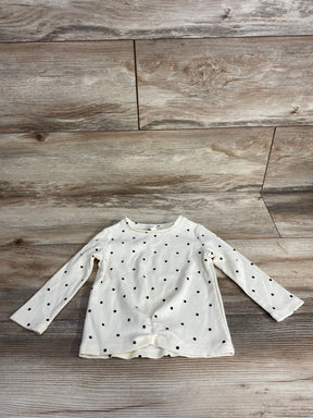 Flat lay of Chelsea and Violet polka dot ribbed long sleeve shirt in cream size 12m with black dots on wood plank floor