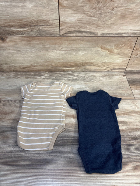 Two baby bodysuits, one tan striped and one solid navy, laid on wood floor
