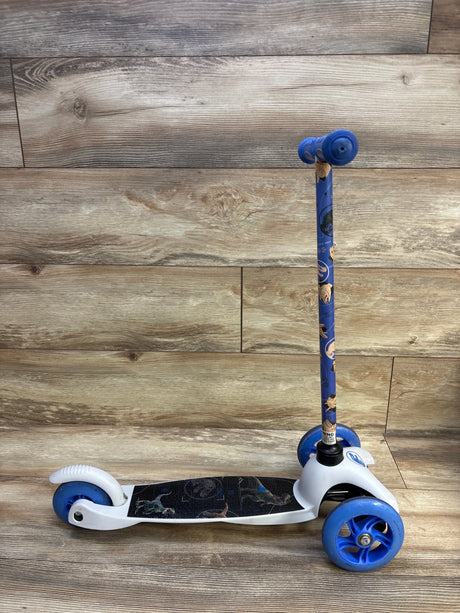 Side view of Jurassic World 3-wheel tilt and turn scooter showing dinosaur deck graphics, blue wheels and handlebars on a wood background