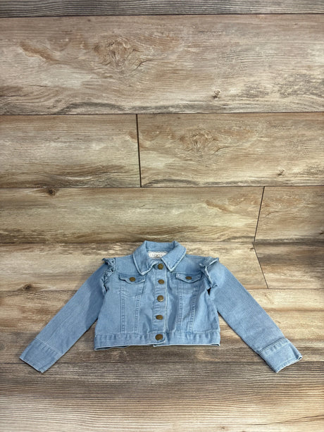 Flat lay of light blue toddler denim jacket with ruffled shoulders and brass snap buttons on wood background