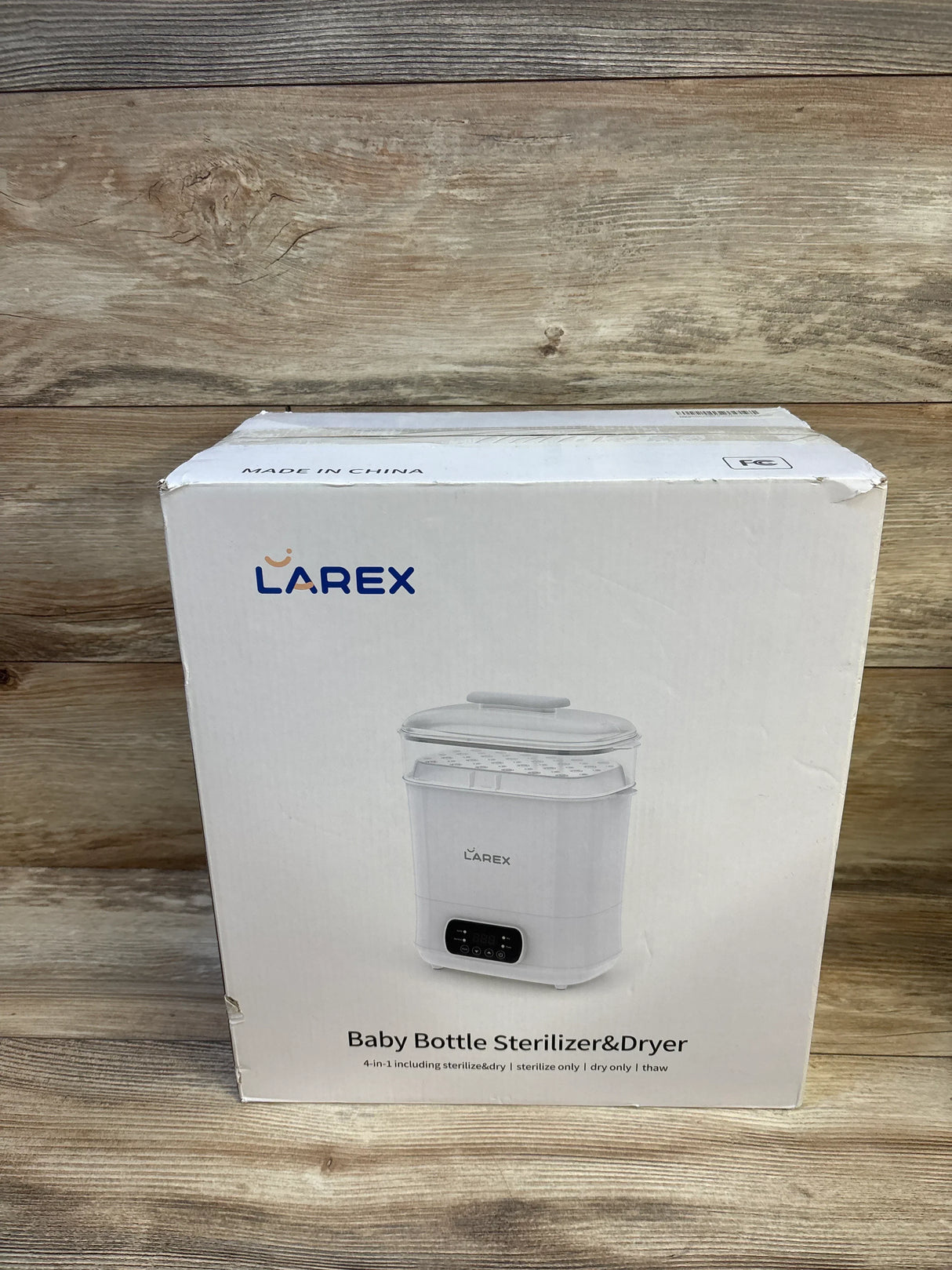 Front of Larex 4-in-1 baby bottle sterilizer and dryer box showing product image and control panel graphic on wood background