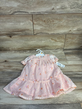 Flat-lay of pink floral baby dress (12M) showcasing ruffled hem and puff sleeves with wood plank background