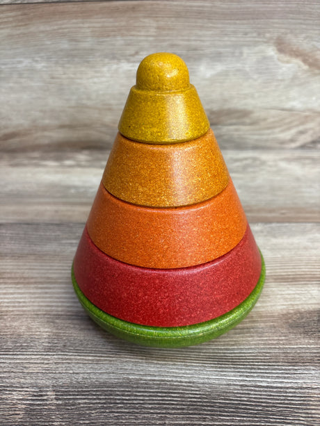 Colorful wooden stacking ring toy with green, red, orange, and yellow rings on wooden surface