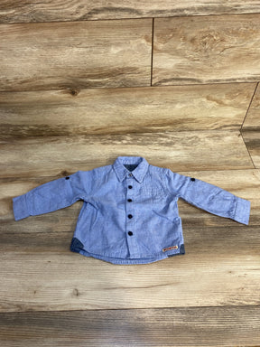 Blue long sleeve baby shirt with black buttons on wood background