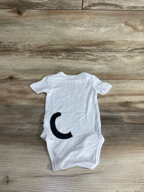 White baby onesie with a large black crescent curl design laid flat on wooden surface