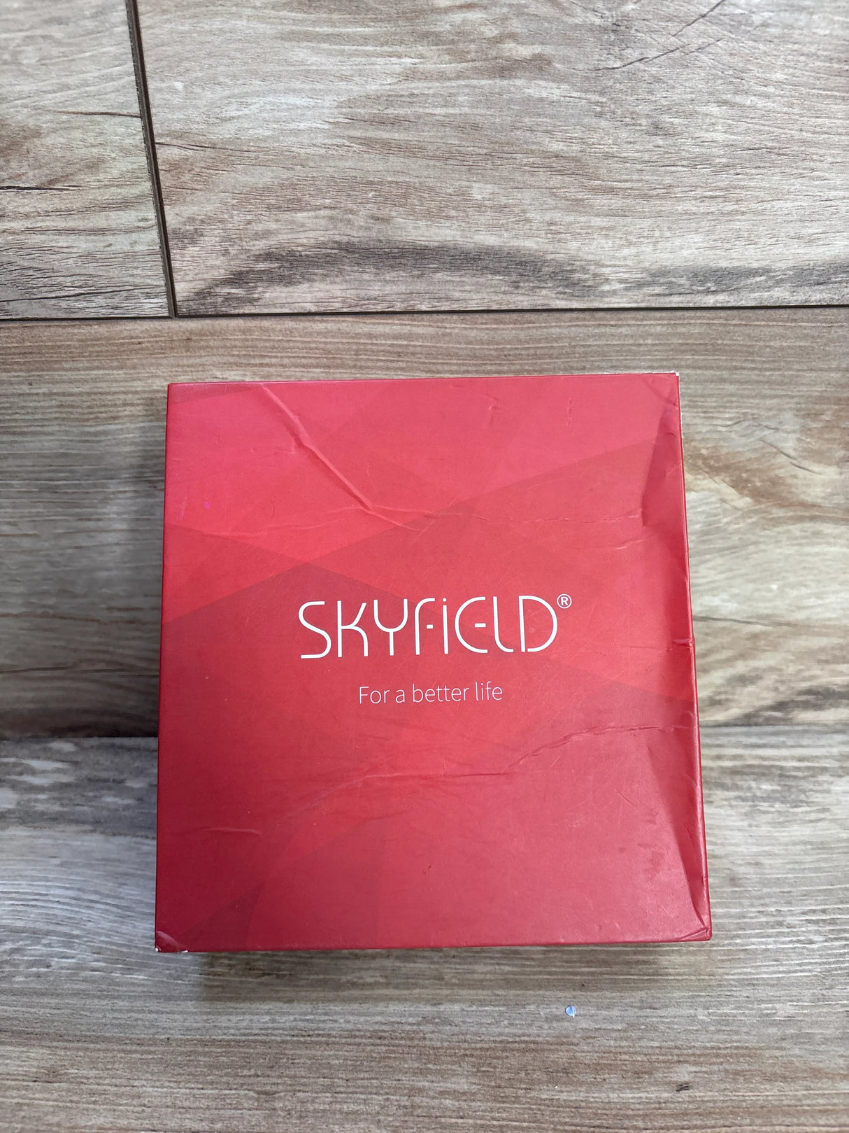 Top down view of Skyfield 4 pack wooden animal puzzles red box showing brand logo and creased packaging on wood floor