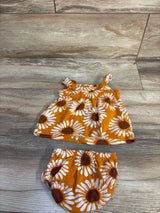 Flat lay of baby 2-piece sunflower top and bloomer set with elastic straps and waistband, white sunflower print on golden orange, on wood floor