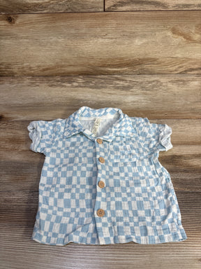 Flat-lay of baby gauze checkered shirt in light blue and white with wooden buttons and puff sleeves on wood background
