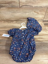 Top-down view of Carter's navy floral bubble romper with bucket hat showing puff sleeves and front buttons on wood floor