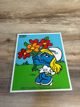 Vintage Smurfette puzzle holding colorful flowers on a wooden surface, kids toy collectible