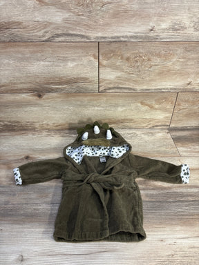 Flat lay of green dinosaur baby bath robe showing hood spikes, printed leaf lining, and tied waist belt on light wood background
