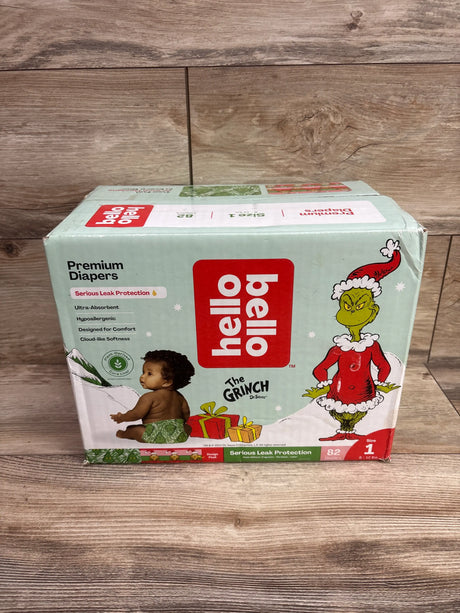 Front view of Hello Bello Premium Diapers, size 1, 82 count, showcasing the Grinch holiday design on a wood floor