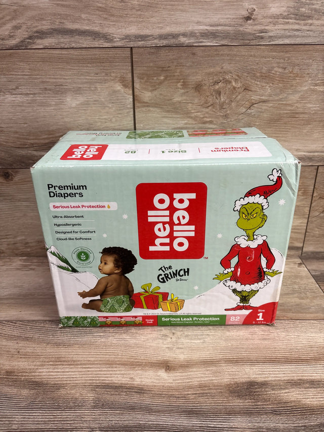 Front view of Hello Bello Premium Diapers, size 1, 82 count, showcasing the Grinch holiday design on a wood floor