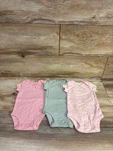 Front view of Carter’s three-pack bodysuits, size 3m, in pink, green, and pale pink with snap closures on wood