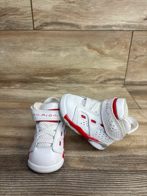 Pair of white and red toddler sneakers with Velcro straps on wooden floor background