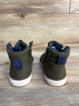 Back view of olive green toddler high top sneakers with white soles on wood floor