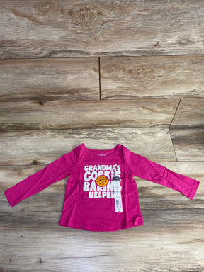 Pink toddler long-sleeve shirt with text Grandma's Cookie Baking Helper and cookie graphic on wooden floor