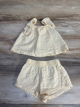 Yellow and white striped baby outfit with ruffled top and shorts, laid on wood floor