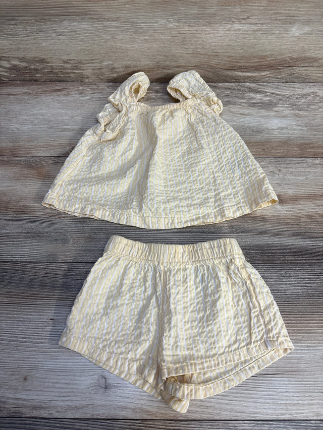 Yellow and white striped baby outfit with ruffled top and shorts, laid on wood floor