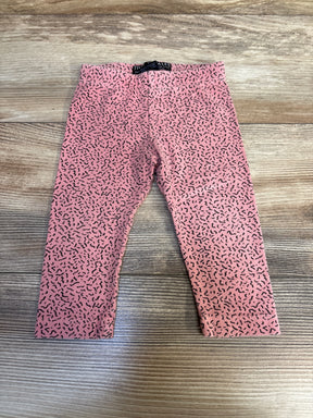 Pink toddler leggings with black squiggle pattern on wooden floor