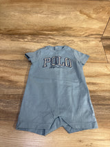 Flat lay of blue Ralph Lauren shortie romper showing POLO embroidered chest logo and snap neck on wood floor