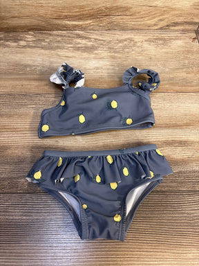 Gray toddler bikini with lemon print, ruffled shoulders and waistband, displayed on wood