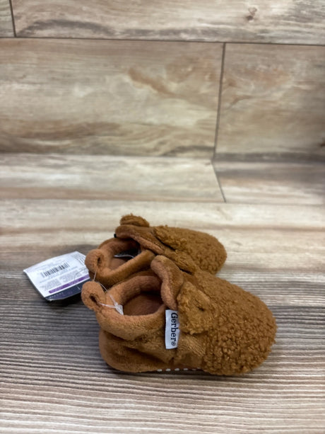 Angled view of brown Gerber fleece-lined soft slipper booties showcasing textured fleece exterior on a wood-look floor