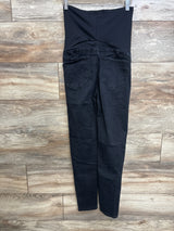Back view of black maternity skinny jeans with tall stretch over-belly panel and back pockets on wood floor background