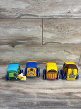 Front view of four K's Kids plush pull-back construction trucks in green, blue and yellow on wood background