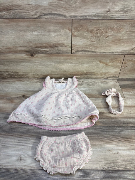 Flat lay of beige 3-piece embroidered gauze baby dress set size 12m with dress, bloomers and headband on wood background