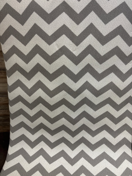 Close-up of Baby Care Play Mat Haute Collection showcasing a gray and white chevron pattern with wood floor background