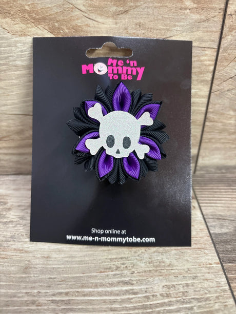 Purple and black skull applique hair bow by Me n Mommy To Be on a black display card.