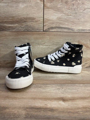 Black high-top kids sneakers with white laces and daisy floral pattern on wood floor