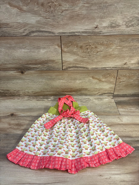 Flat lay of pink Baby Yoda print toddler dress showing green polka dot halter tie and pink ruffle hem on wood background