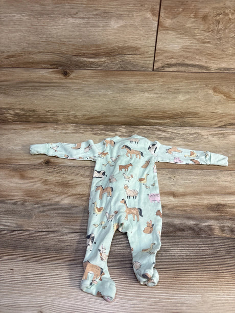 Flat lay of newborn mint green farm animal footed sleeper showcasing all-over farm animal print on wood background