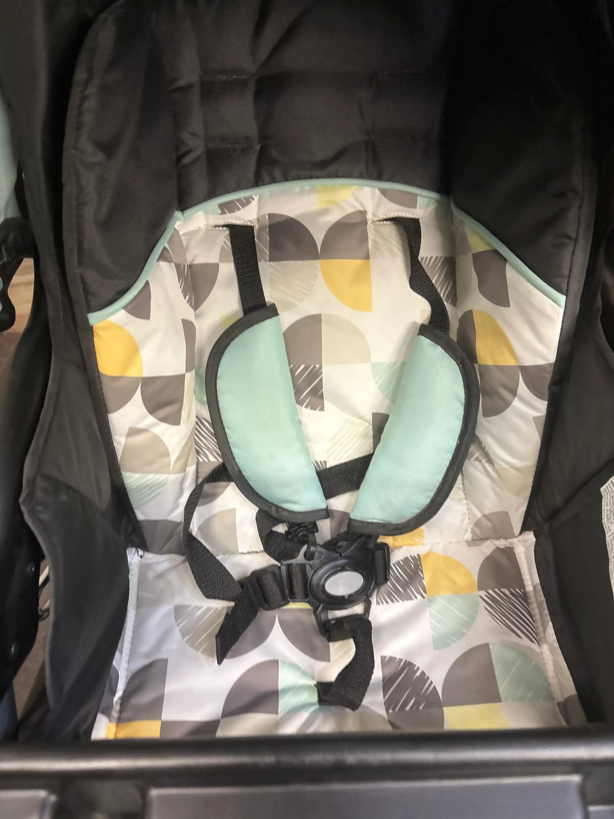 Close-up of Baby Trend EZ Ride Stroller in Doodle Dots showcasing patterned seat, five-point harness, and mint shoulder pads