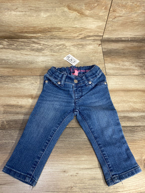 Children's blue denim jeans with elastic waistband and tag on wooden floor