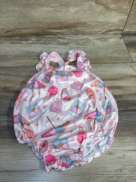 Top view of pink baby crossback romper with ruffled straps, beach print, and snap crotch on wood floor