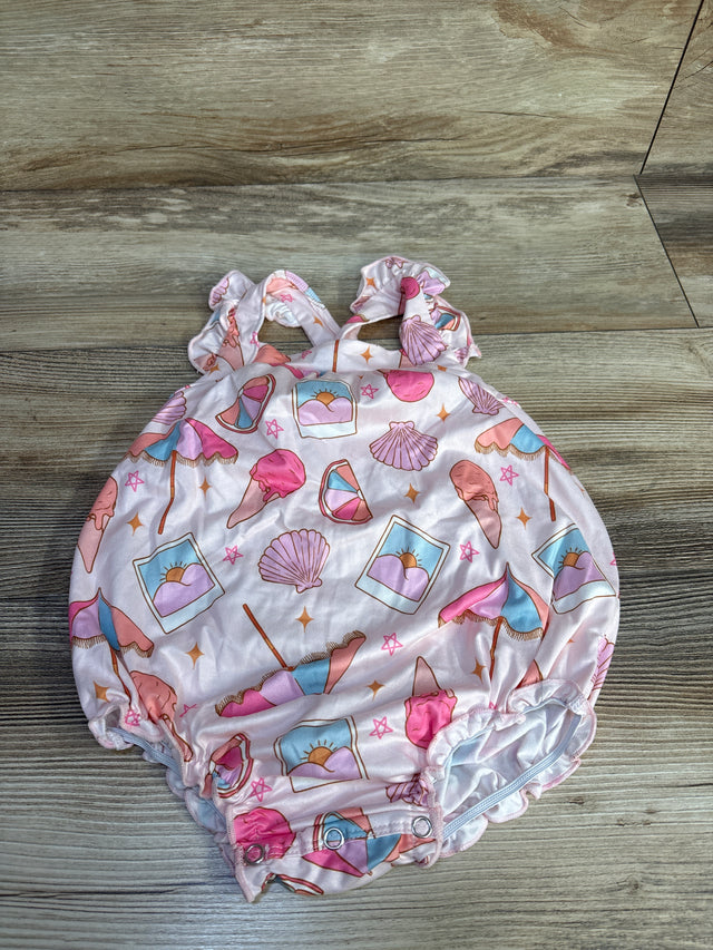 Top view of pink baby crossback romper with ruffled straps, beach print, and snap crotch on wood floor