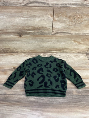 Green kids sweater with black leopard print, long sleeves, ribbed cuffs and hem on wood floor