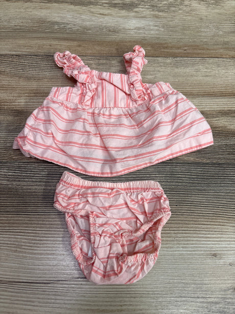 Top-down view of Just One You newborn pink striped dress and bloomers showcasing ruffled straps on wood-grain background