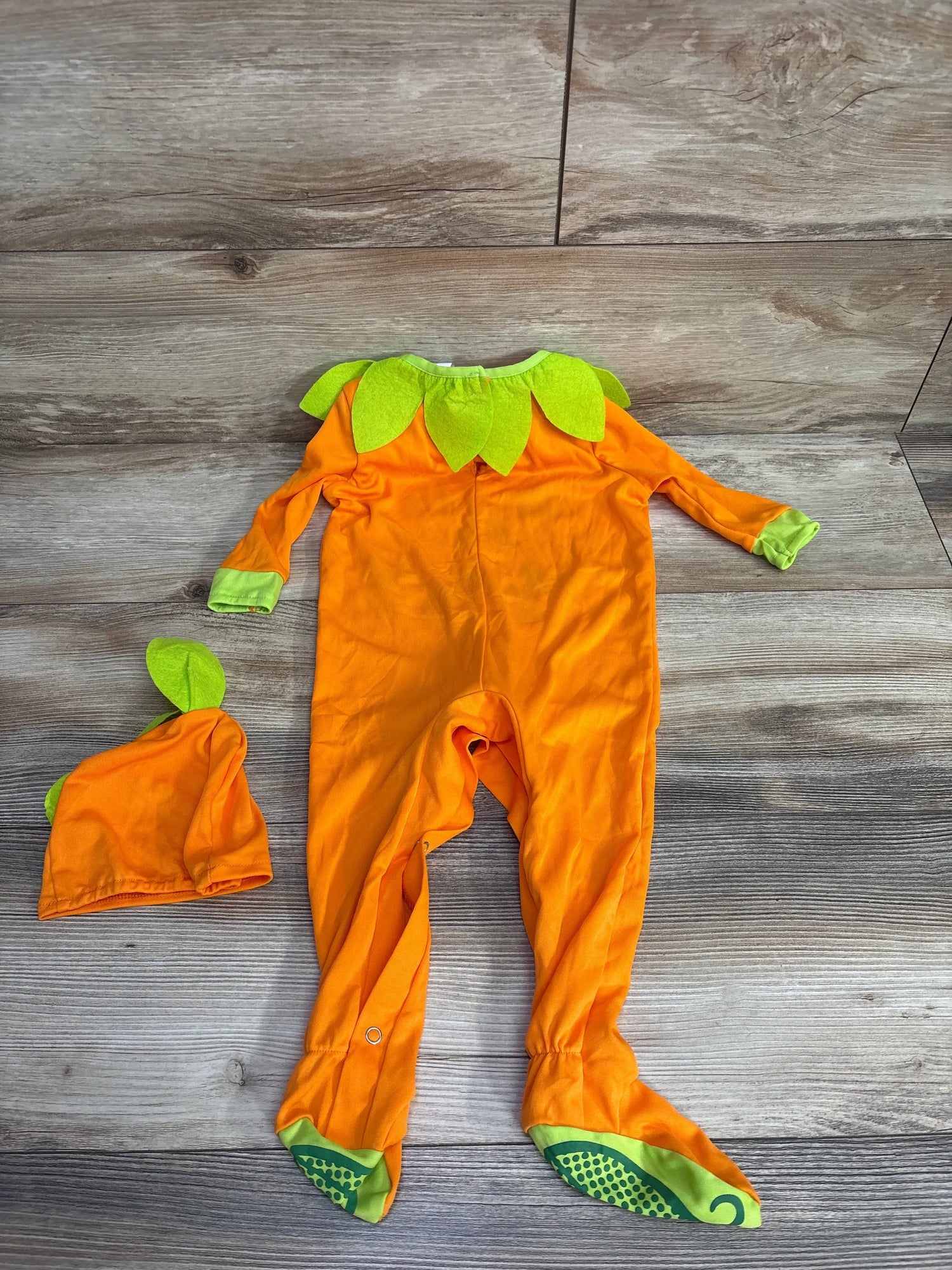Orange pumpkin-themed baby onesie with green leaf accents and matching hat, perfect for Halloween or fall.