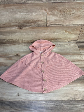 Pink knit hooded toddler cape with buttons, displayed on wood floor