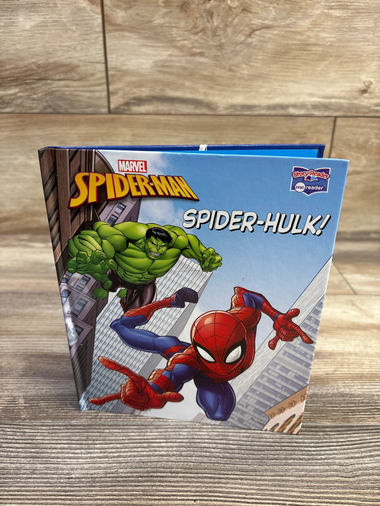 Front cover of Marvel Spider-Man Spider-Hulk! hardcover children's book showing Spider-Man and Hulk over skyscrapers on a wood tabletop